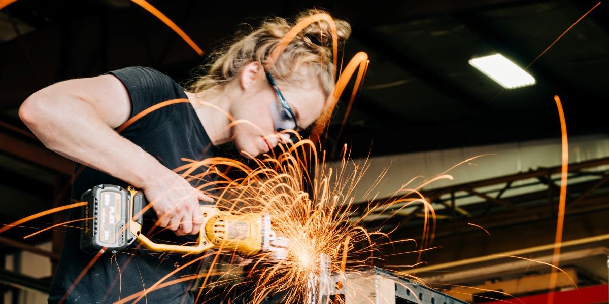female trade worker grinds and cuts metal